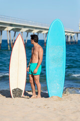 Young handsome man with a surfboard at a beach