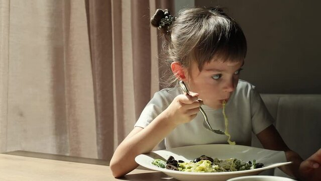 Cute little girl 5-6 years old enjoying cheesy spaghetti