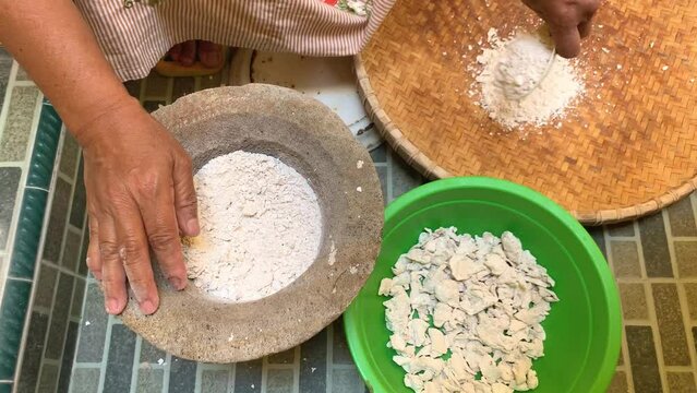 Pounding Umbi Gadung or Dioscorea hispida with mortar and pestle