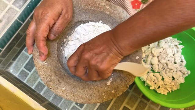 Pounding Umbi Gadung or Dioscorea hispida with mortar and pestle