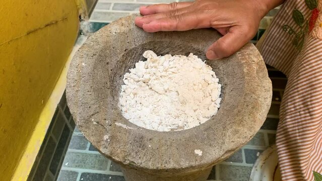 Pounding Umbi Gadung or Dioscorea hispida with mortar and pestle