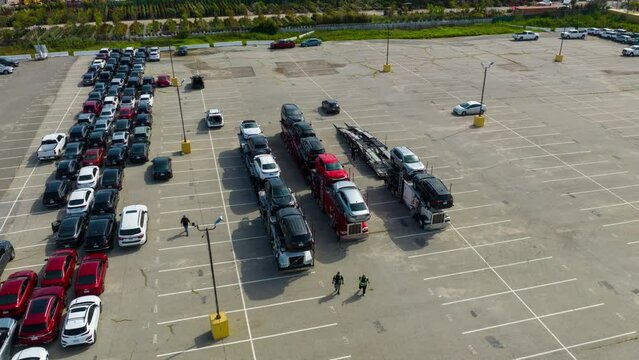 Loading Vehicles on Car Carrier or Truck. Aerial top down view of a car carrier trailer (car-carrying trailer, car hauler, or auto transport trailer) with a new cars.  Time Lapse