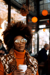 Obraz premium Beautiful modern Afroamerican woman outdoors at a cafe, blurred background 
