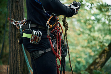 Close up particle view. Man is doing climbing in the forest by use of safety equipment