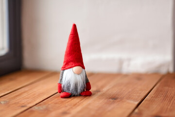 christmas, decoration and winter holidays concept - close up of gnome on wooden window sill at home
