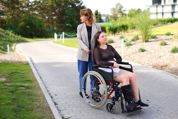 A female volunteer helping a woman in a wheelchair in the garden of an retirement home.