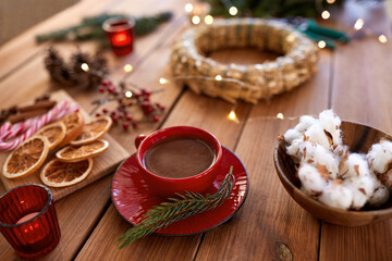 winter holidays, diy and hobby concept - close up of christmas wreath making stuff, decorations and hot chocolate on wooden table