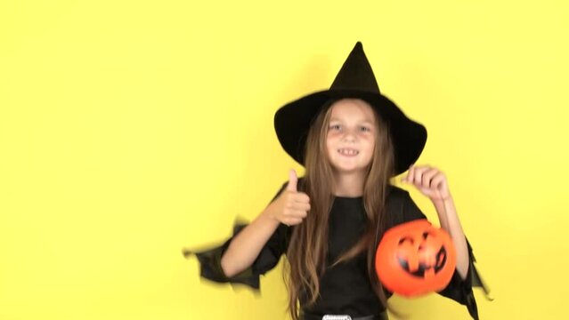 A little girl on a yellow background shows emotions, the concept of the holiday Halloween