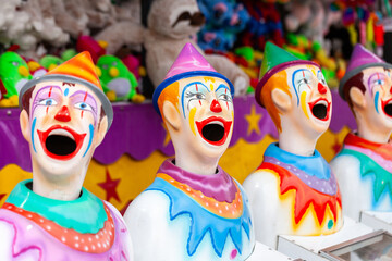 Brightly painted clowns at carnival sideshow alley