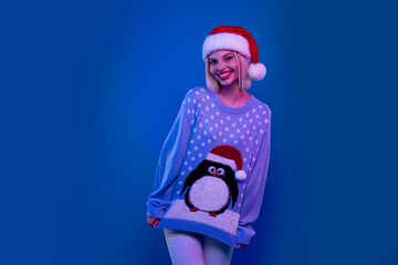 Photo of shiny sweet lady santa helper dressed ugly print sweater enjoying xmas empty space isolated blue color background