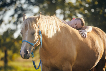 Man lying embracing of therapy horse. Themes hippotherapy, care and friendship between people and...