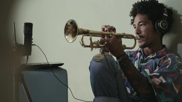 Young African American man recording music, playing latin jazz trumpet 