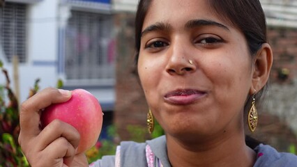 Happy young girl biting an apple at home. Beautiful Asian young woman eating fresh apple fruit outdoors. Healthy fresh food and vegetarian dieting concept. 4k video.