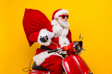 Photo of cool bearded santa saint nicholas grandfather riding moped delivering big sack with purchases isolated on yellow color background