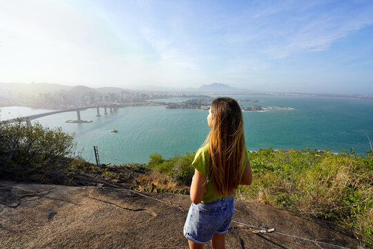 Back view of woman admiring the landscape from lookout top view at sunset, Vitoria, Espirito Santo, Brazil
