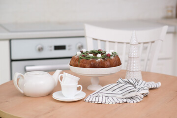 Christmas home interior in white kitchen-Christmas chocolate bundt cake with fresh berries and rosemary. Winter baking at Christmas or New Year with decorations. Ceramic christmas tree.