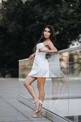 Photograph, portrait of a beautiful young brunette Armenian girl in a white dress in a park on the street outdoors.