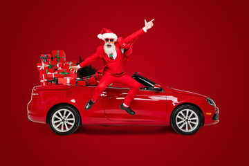 Full length body size view of attractive cheerful Santa jumping near car having fun isolated over...