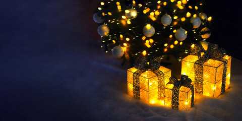 Decor of golden glowing boxes with bows under the Christmas tree. New Year's Eve banner.