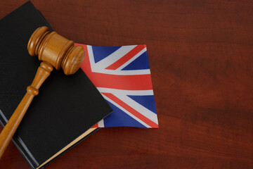 Gavel and legal book on wooden table with united kingdom flag. Copy space for text.