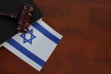 Judge gavel and legal book with flag of Israel on table.