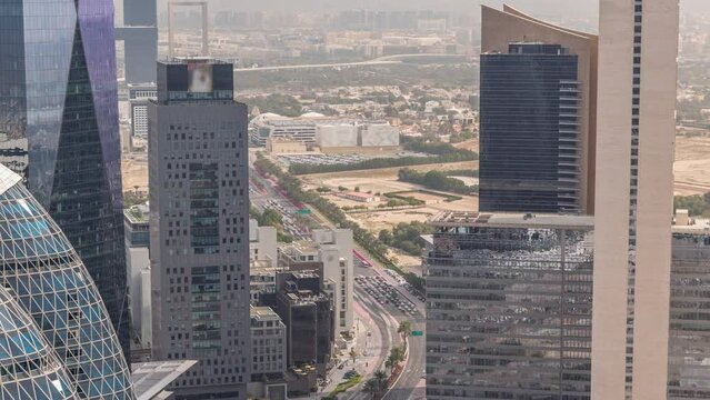 Skyline view of the high-rise buildings around traffic on the road in Dubai aerial timelapse, UAE. Skyscrapers in International Financial Centre financial hub from above. Deira district on background
