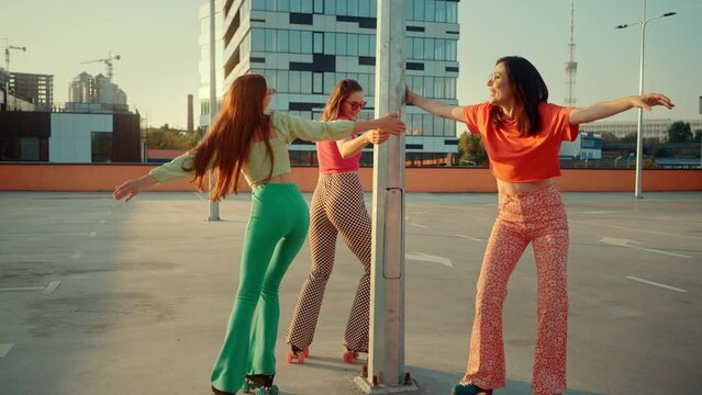 Energetic females moving around pole using retro rollers