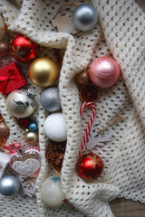 Various colorful Christmas ornaments, small presents and seasonal spices on white knitted blanket. Top view.