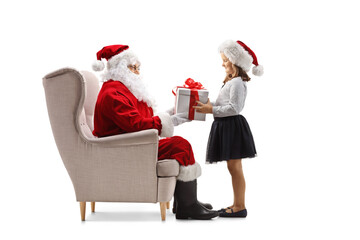 Girl holding a present box in front of santa claus seated in an armchair