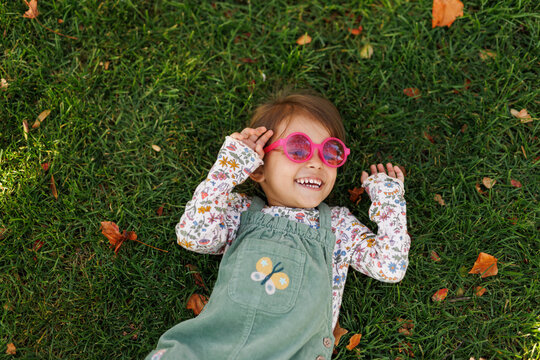 Cute little girl in an autumn park on grass. Toddler girl having fun outdoor. Autumn lifestyle photo for advertising tape.