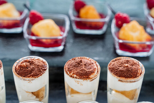 Trifle liquid cake in cups shot close-up, sprinkling dessert with cinnamon on top, shot glass with treats.
