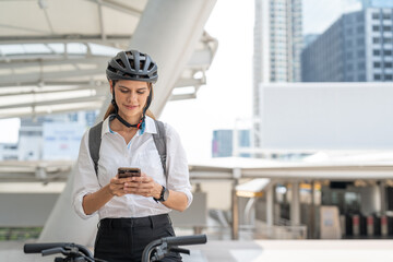 Businesswoman using smartphone while riding bicycle. Woman commuting on bike go to work in city....