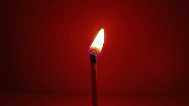 burning matchstick on red background