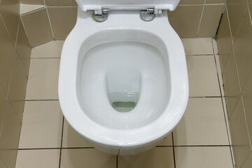 Fototapeta premium The washroom boasts a modern design with a clean toilet bowl and beige ceramic tiles.