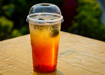 A cup of cold, refreshing orange-color Vietnamese fruit juice isolated on a table in a sunny day