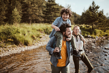 Young family walking across a mountain stream in nature