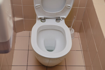 This public bathroom features a sanitary toilet seat and brown tile flooring for a sleek interior look.