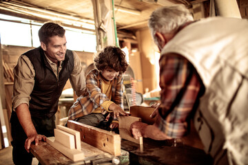 Three Generations of Carpenters : Grandfather, Father, and Son working in the Workshop