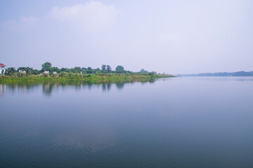 Reflection of trees in the lake water against the blue sky landscape countryside in Bangladesh