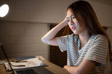 A young woman works on her laptop at home. It is characterized with headaches that occur when...