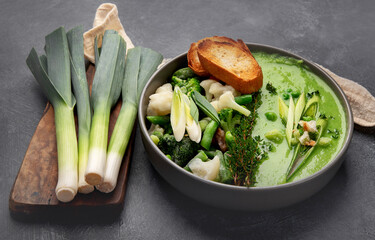 Delicious healthy green cream soup in a bowl with croutons on table.