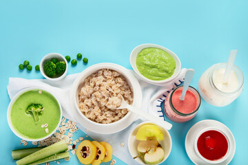 Bowls with healthy baby food on blue background.