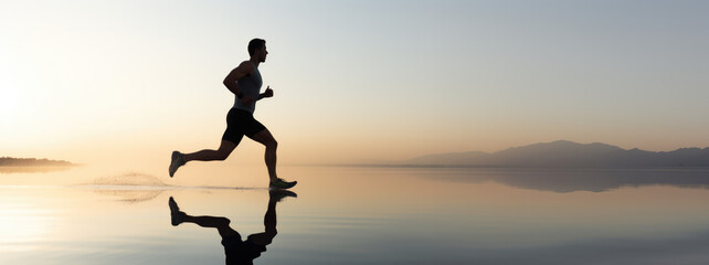a man running at sunrises with reflection and soft sky, background changing from light orange to blue, minimalist sport banner in panoramic view, space for text