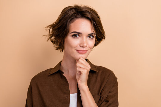 Photo of good mood woman with bob hairstyle dressed brown shirt hold finger on cheen think business isolated on beige color background