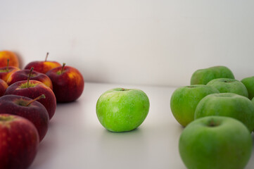 Two groups of green and red apples. One apple in the center. Organic fresh fruits and image of autumn harvest