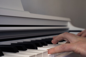 Mens hands playing on white upright piano. Musical theme. Piano keyboard