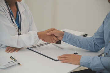 Smiling young female doctor shake hand close health insurance deal with elderly patient at...