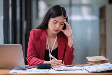 Stressed business woman working from home on laptop looking worried, tired and overwhelmed.