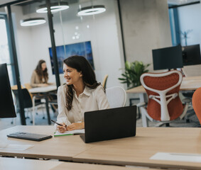 Young business woman working on laptop in the modern office