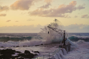 Dock and crane in the fishing village of El Pris, at sunset on a day of strong waves (Tacoronte, Tenerife)